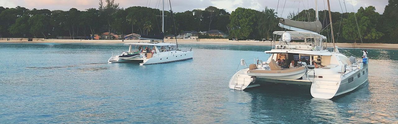 A tranquil marina scene with sailboats anchored on calm turquoise water and a tree-lined shore under a pastel sky.