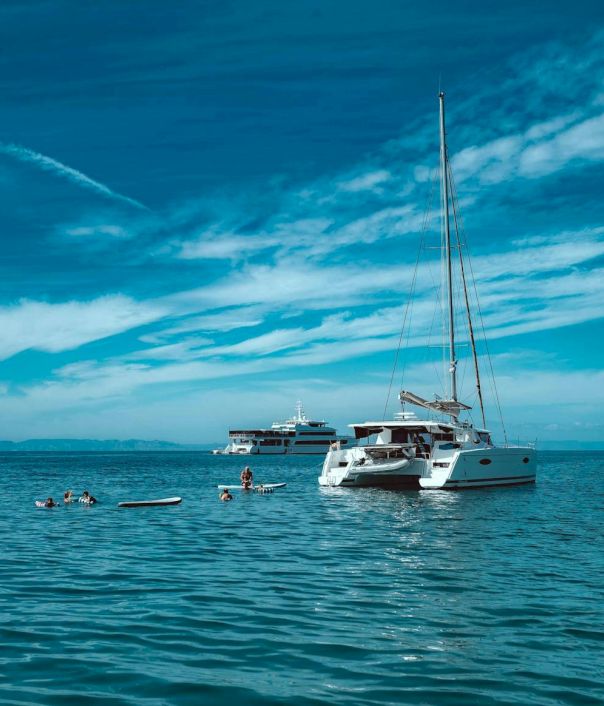 People snorkelling near two anchored boats in clear blue sea under a bright sky.